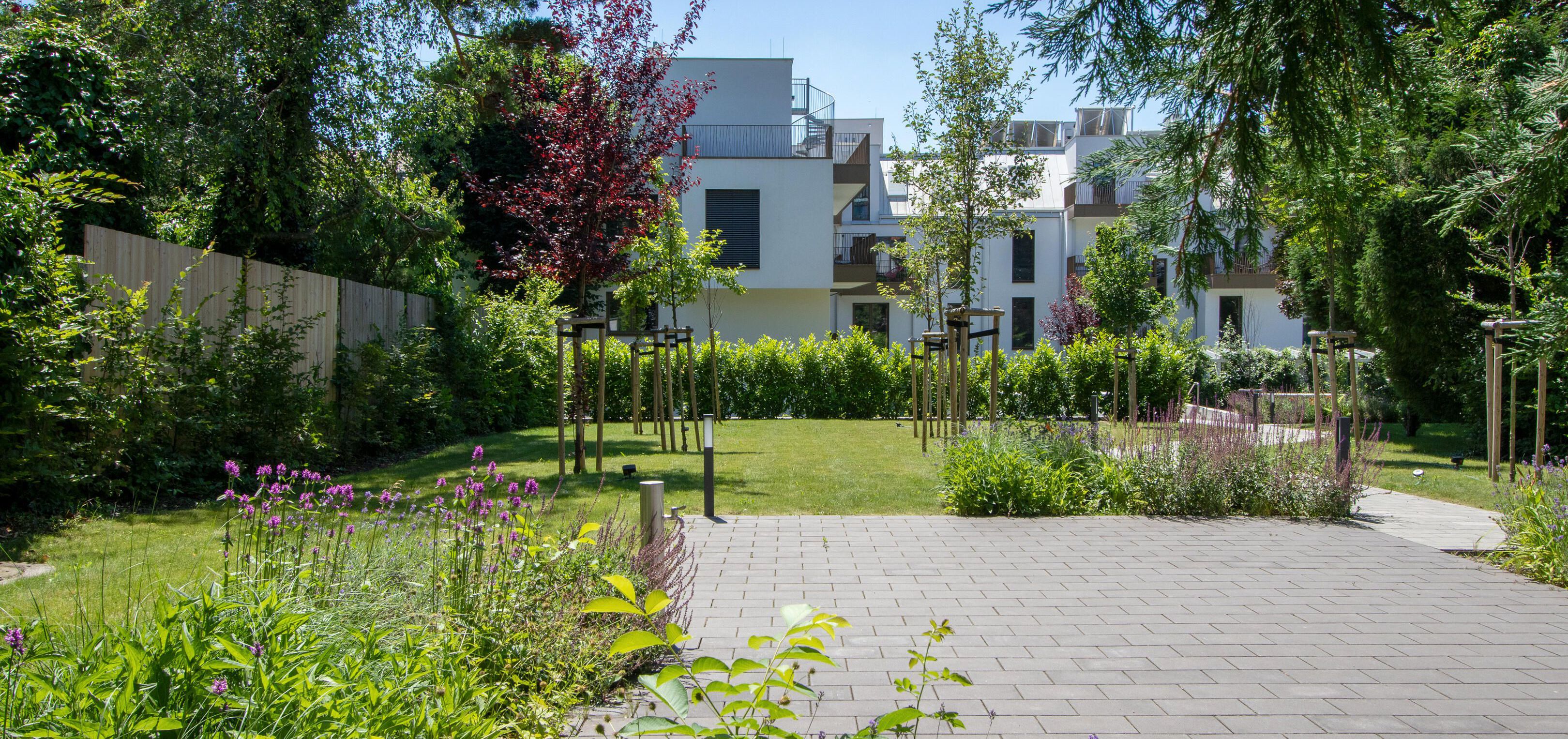 Blick auf den grünen Garten im Innenhof mit gepflasterter Terrassenfläche
