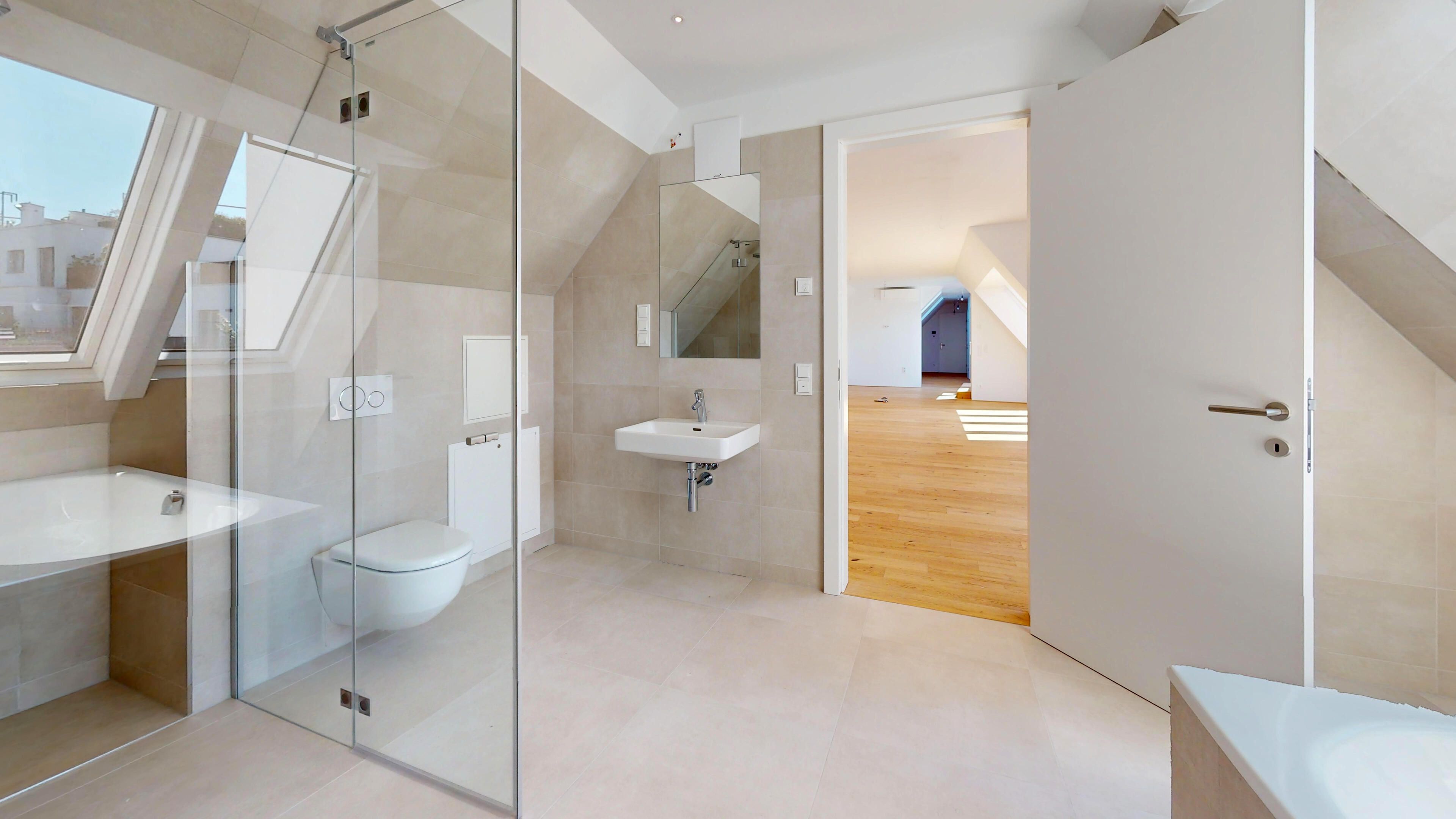 Ansicht eines hellen Badezimmers mit Badewanne, Dusche, Handwaschbecken und Toilette