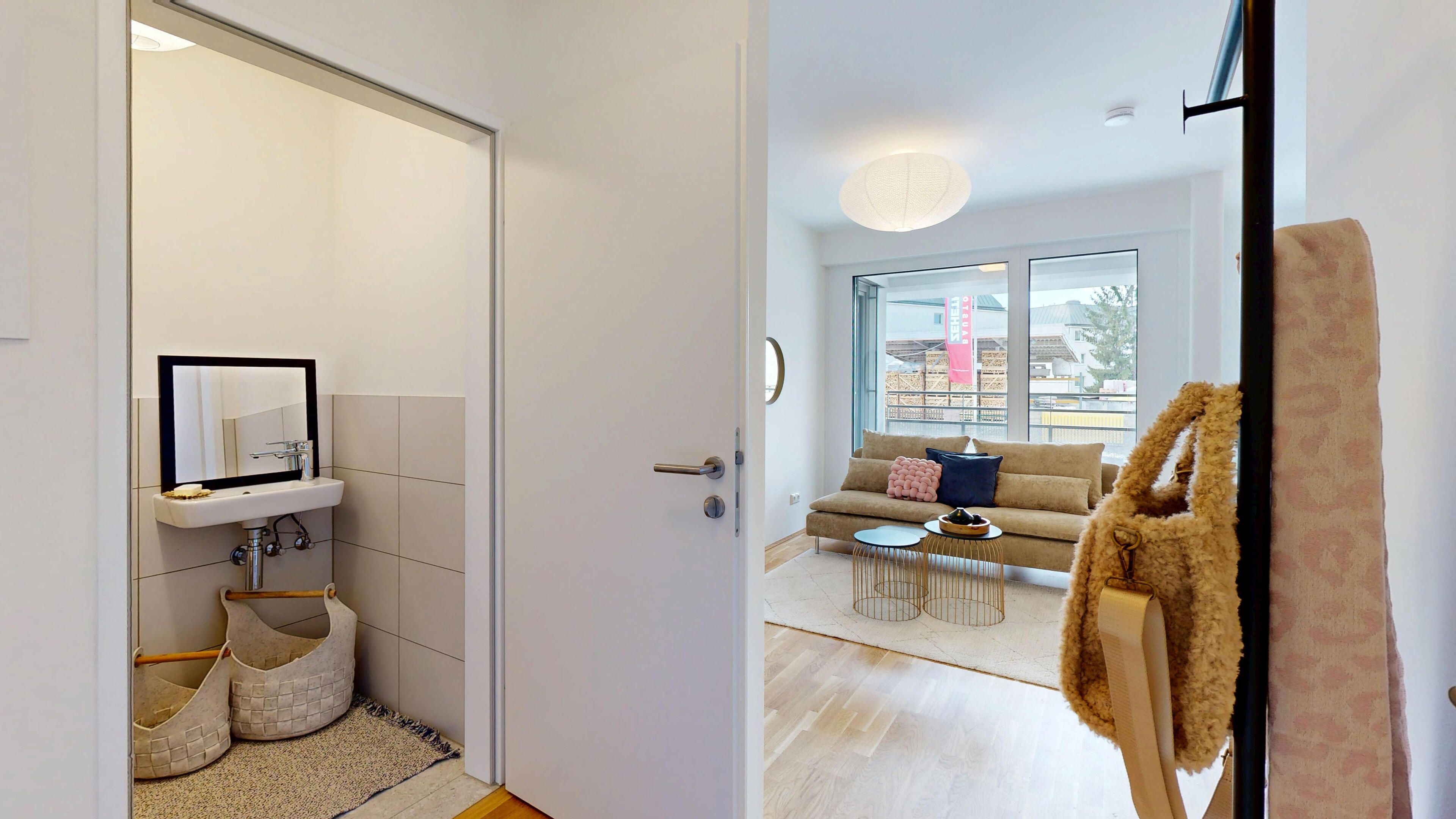 Ansicht des GästeWC mit Handwaschbecken, Innentür und mit Blick ins Wohnzimmer