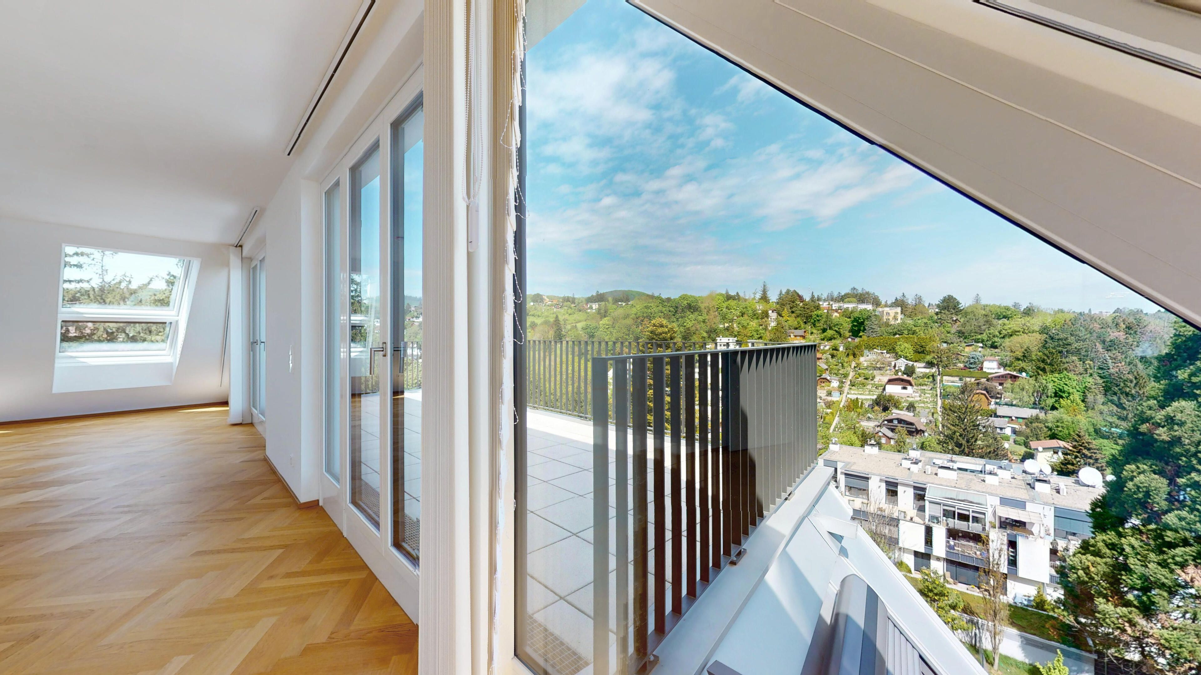 Ansicht des Wohnraums mit Blick durch die Fensterfront hinaus ins Grüne