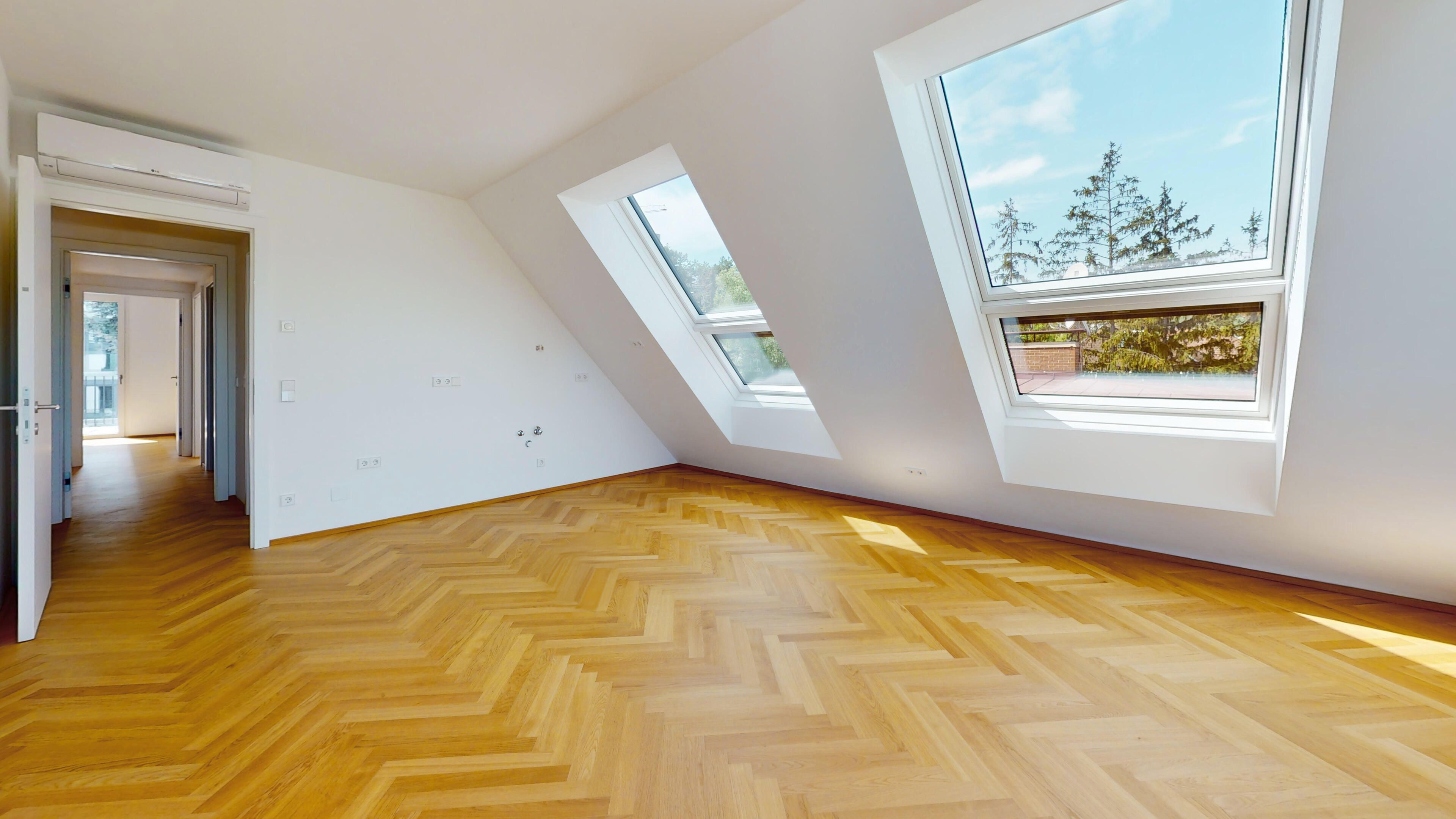 Ansicht eines hellen Wohnraums mit Fenstern und mit Fischgrätparkettboden