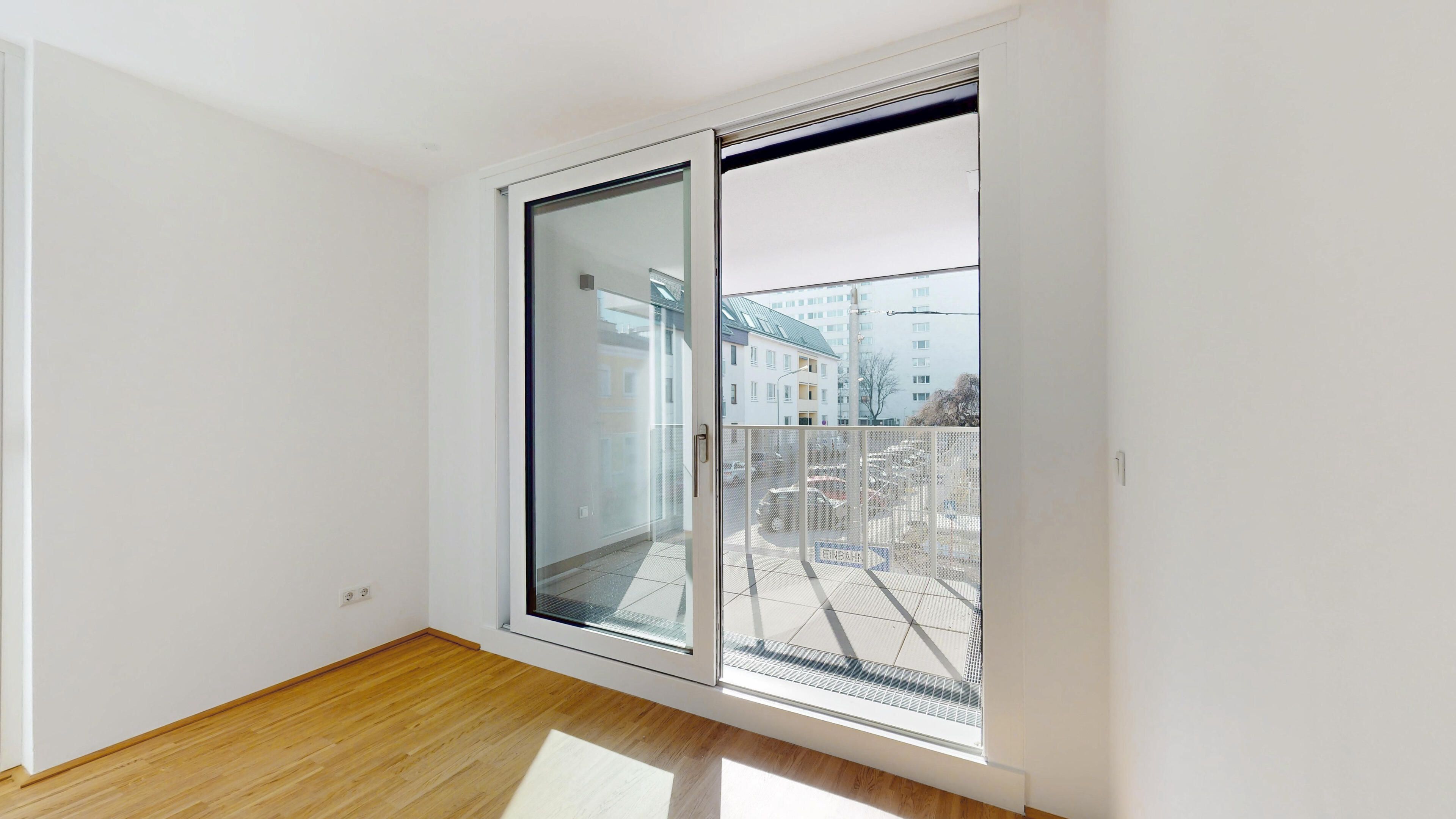 Ansicht eines hellen Zimmers mit Blick Richtung Terrasse, Zugang über eine großzügige Terrassen-Schiebetür