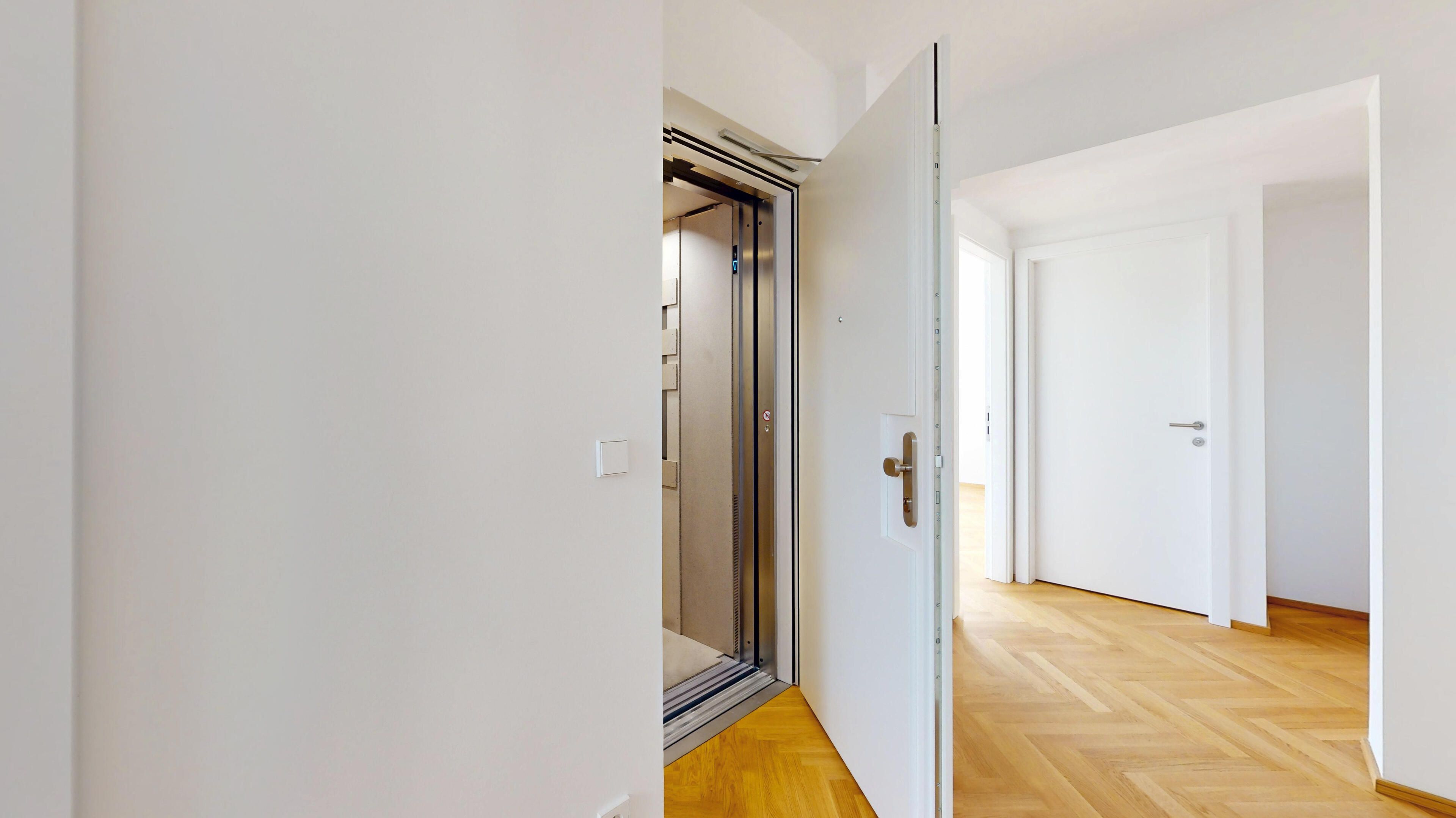 Ansicht eines Flurs mit direkter Liftfahrt in die Wohnung, Blickrichtung zur Tür und zum Lift