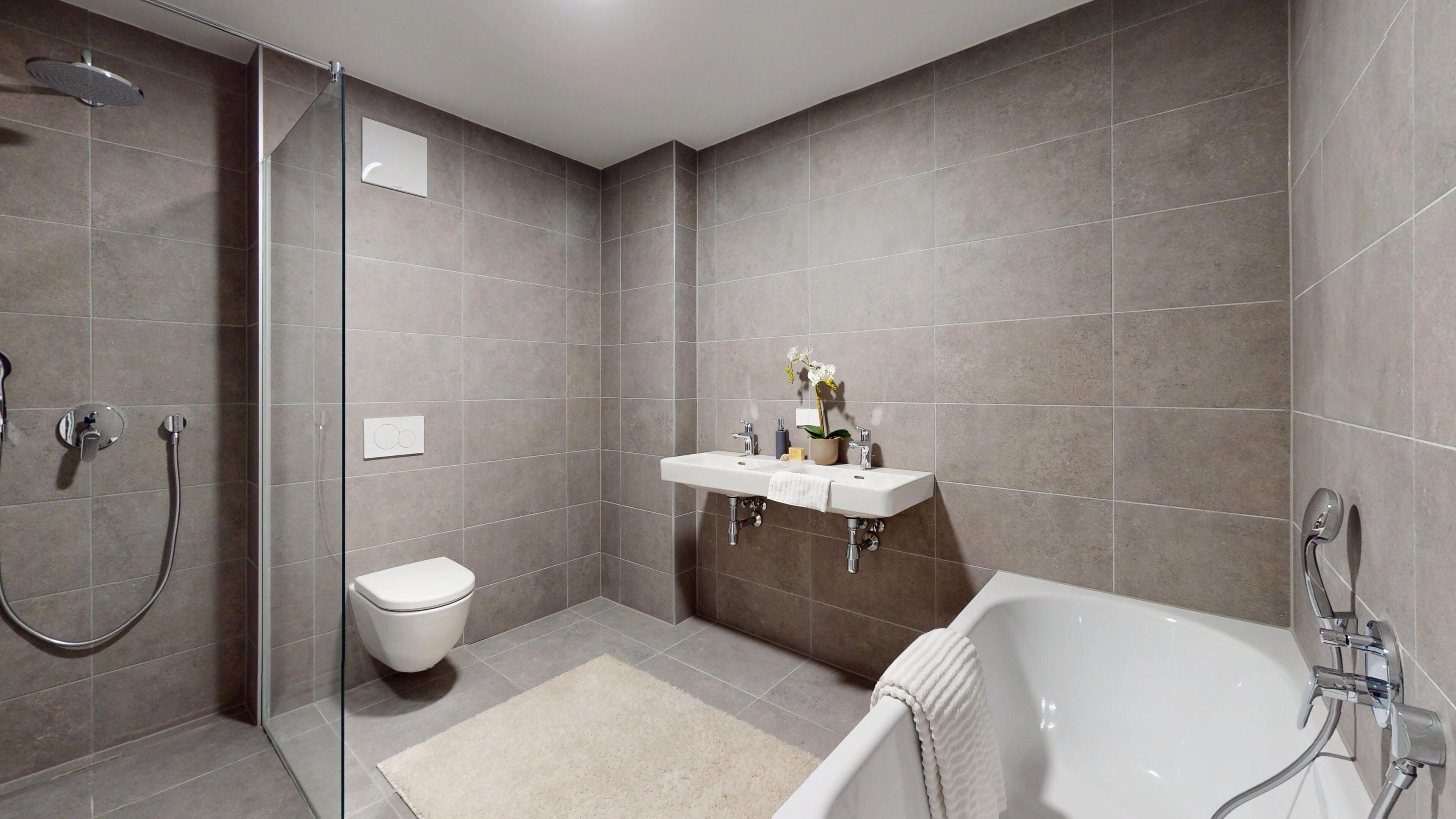 Ansicht eines Badezimmers mit Dusche, Bad, Doppelwaschbecken und Toilette
