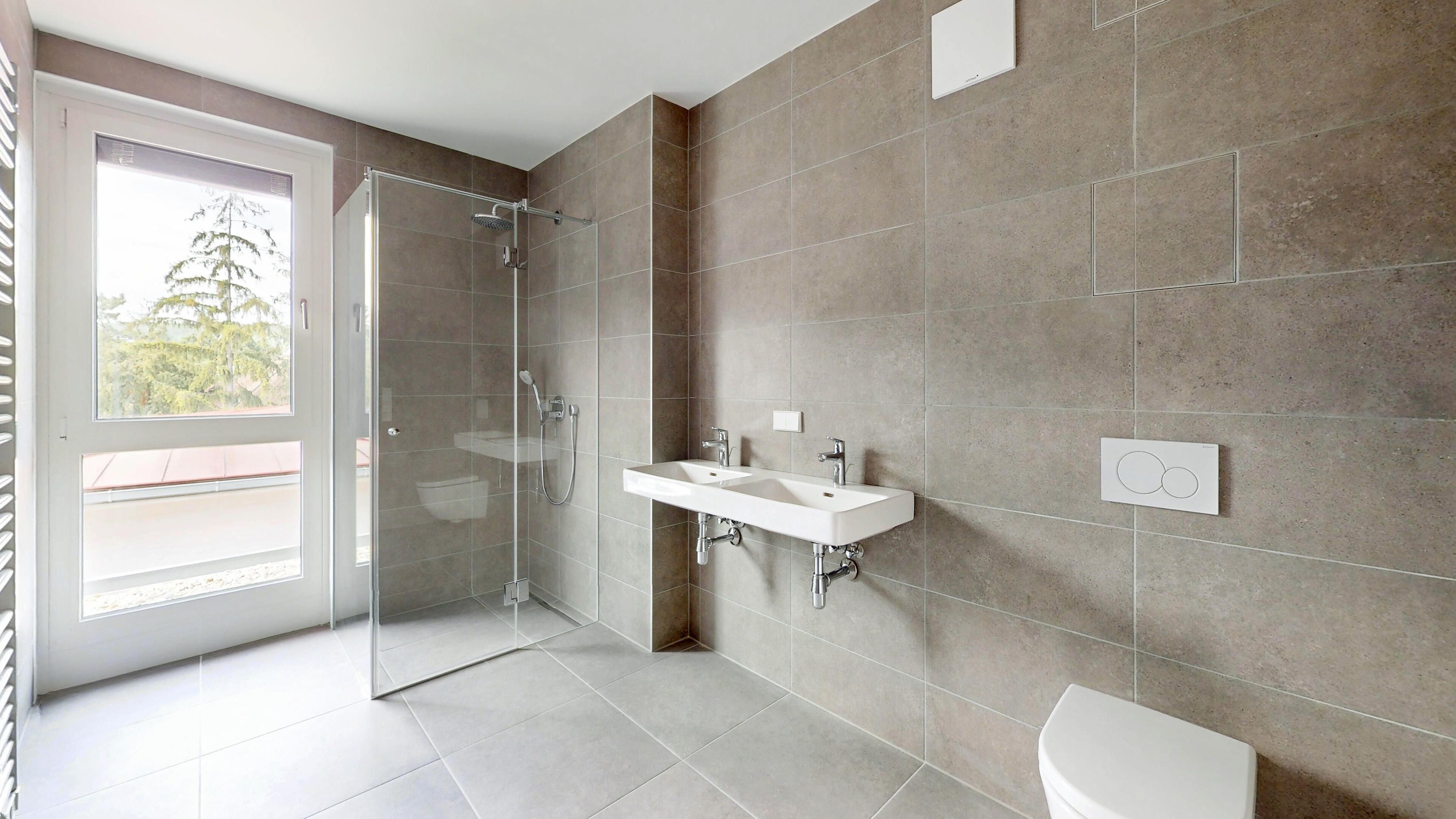 Ansicht des Badezimmers mit Fenster, Dusche, Handwaschbecken und Toilette