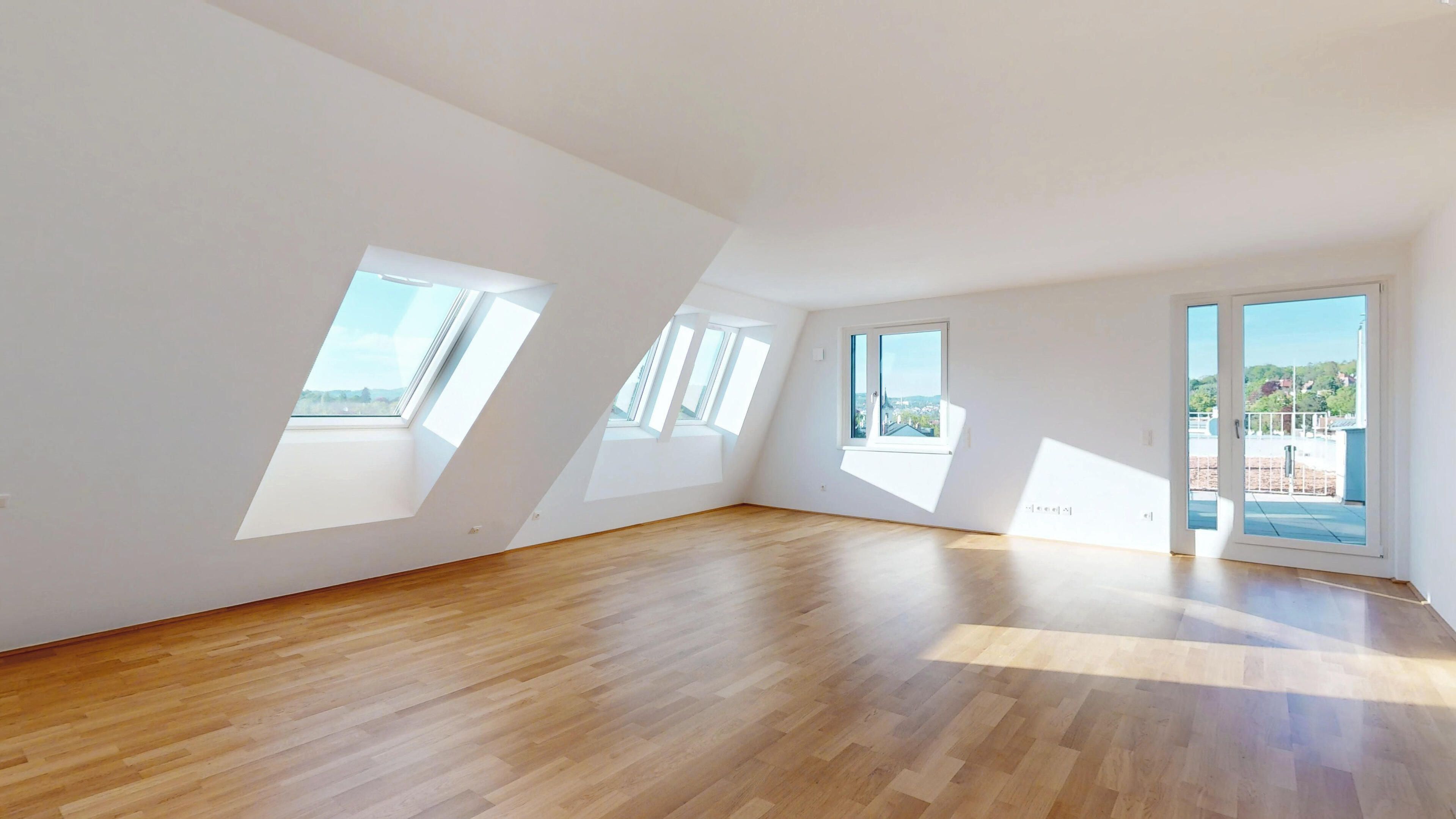 Ansicht eines geräumigen Wohnzimmers mit Dachfenstern und Zugang zur Terrasse