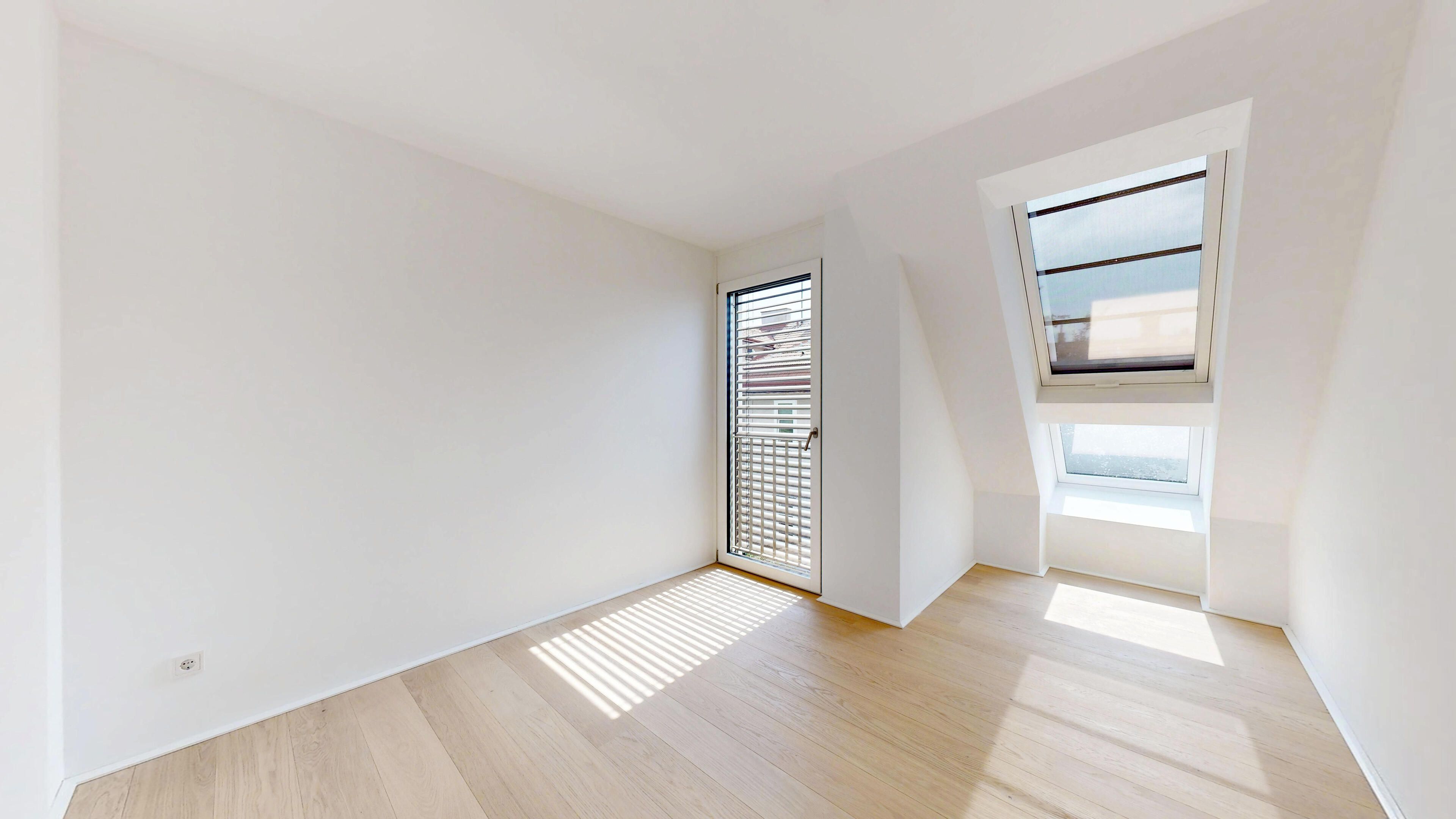 Schlafzimmer mit heimeliger Schräge und hellen Fensterfronten