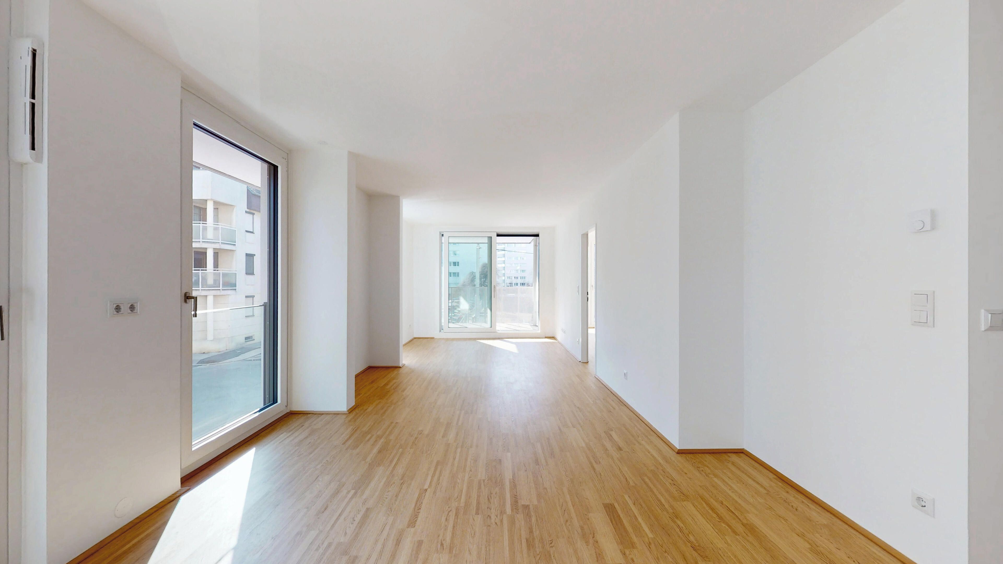 Ansicht eines geräumigen Wohnraums mit Zugang zum Balkon und Blick ins Schlafzimmer
