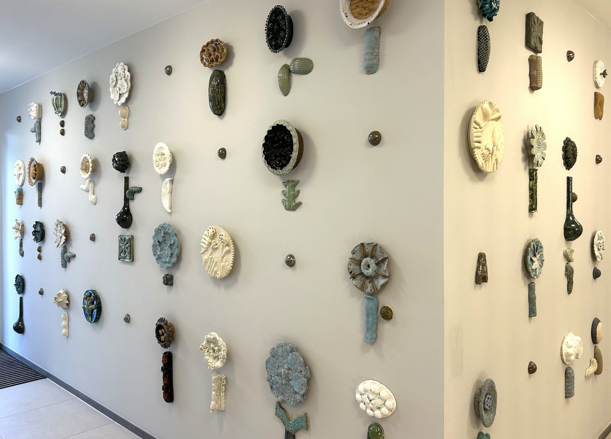 Das Kunstwerk ist eine Installation keramischer, floraler Elemente in individuell gearbeiteten blütenähnlichen Formen. 