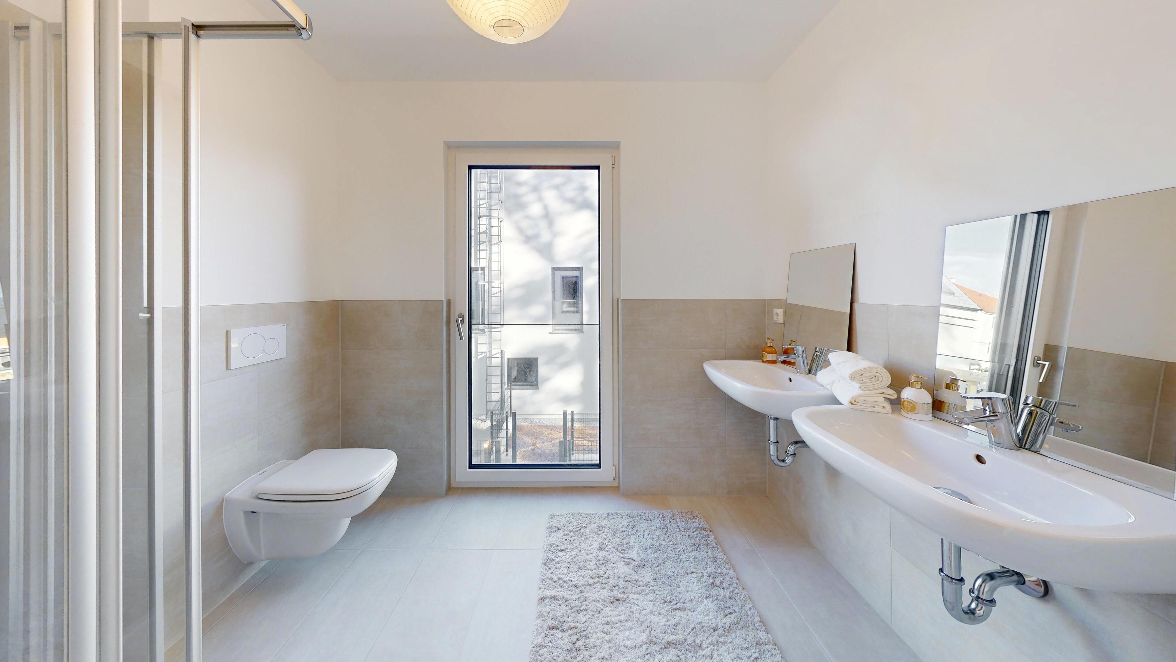 Ansicht eines Badezimmers mit Doppelwaschbecken und WC